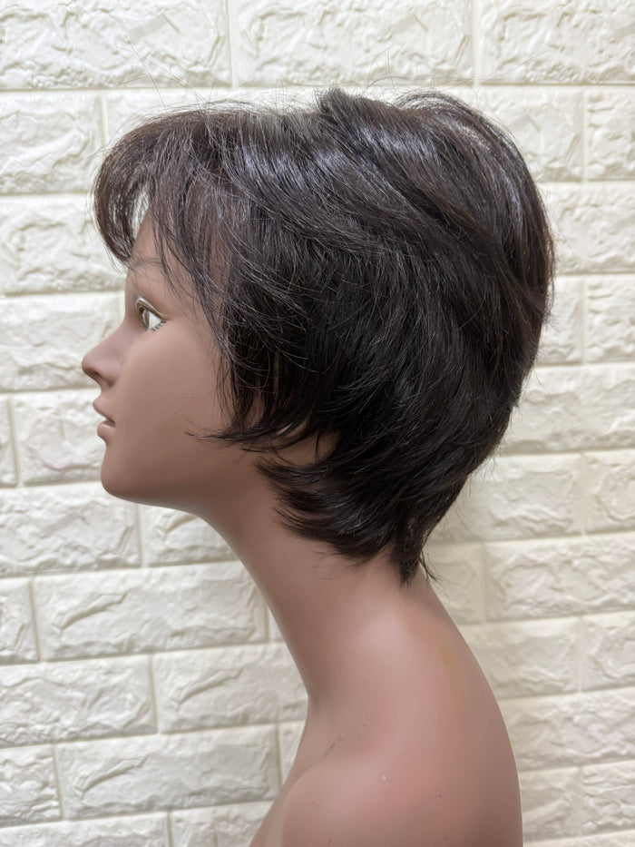 A short, layered wig with dark brown to black hair styled in a side-swept bob, displayed on a mannequin head against a light beige faux brick wall background.